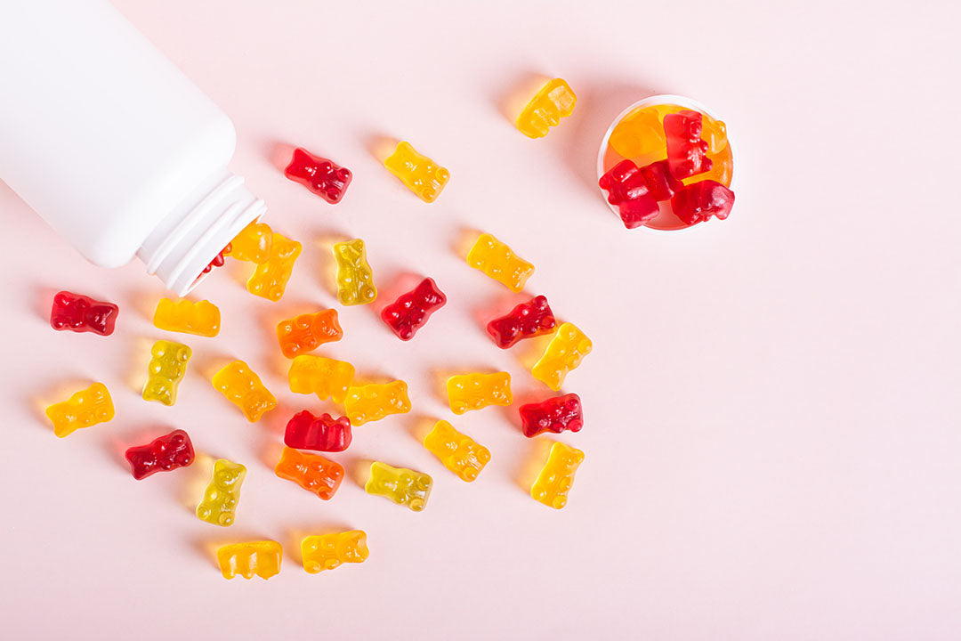 Premium gummy supplement manufacturing at Biowell Labs—colorful gummy bear vitamins spilling from a white bottle, representing high-quality private label supplements, contract supplement manufacturing, and Halal and Kosher certified supplements in a Health Canada approved facility.