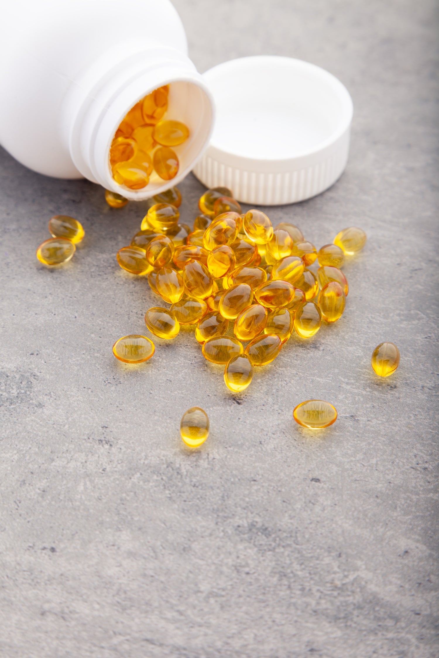 Premium softgel production at Biowell Labs—golden softgel capsules spilled from a white bottle, highlighting high-quality contract supplement manufacturing and private label nutraceuticals in a Health Canada approved facility.