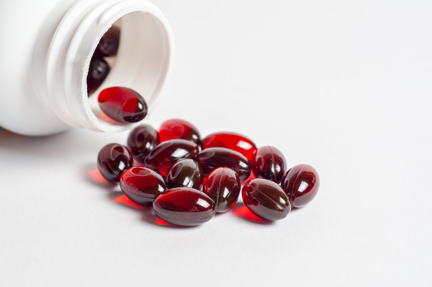 Premium softgel supplement manufacturing at Biowell Labs—high-quality red softgel capsules spilled from a white bottle, highlighting contract supplement manufacturing and private label nutraceutical production in a Health Canada approved facility.